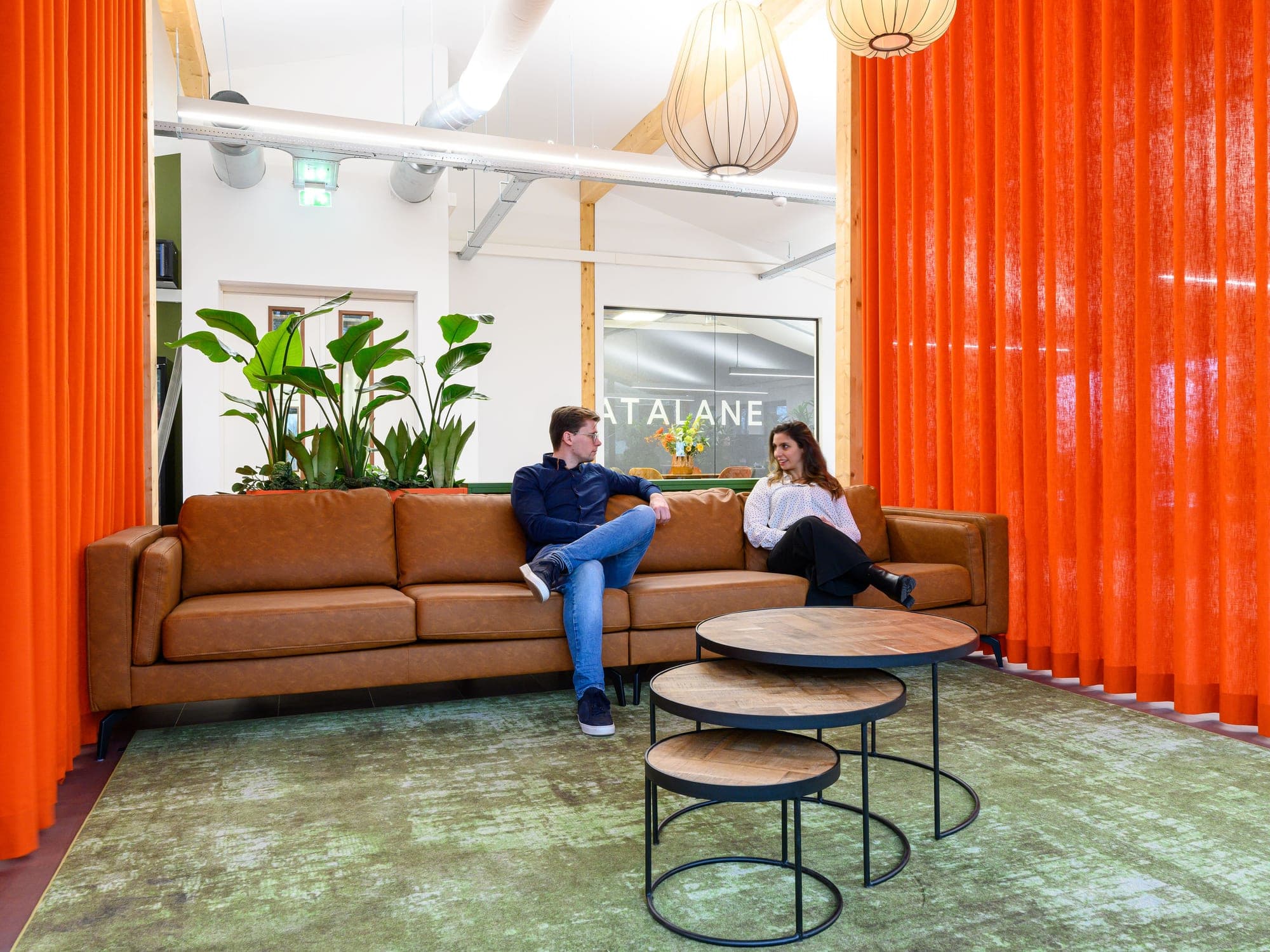 Two DataLane colleagues talking on the sofa in the office lounge